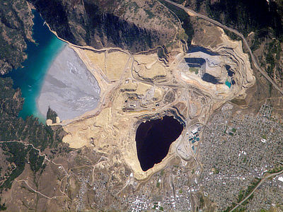 Figure 5.11: The Berkeley Pit and associated tailings pond. This open pit copper mine reaches a depth of about 540 meters (1780 feet), and is filled to a depth of about 270 meters (900 feet) with metal-laden acidic water. The mine is 1.6 kilometers (1 mile) long and 0.8 kilometers (0.5 miles) wide.