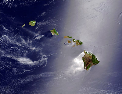 Figure 9.13: The effect of the northeast trade winds is seen in the shiny, highly reflective, calm water southwest of Hawai’i Island, where the ocean lies in the lee of the island’s big volcanoes.