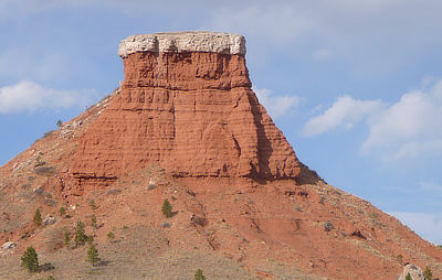 Figure 4.12: Red Butte, near Casper, Wyoming, rises high above the easily erodible red Spearfish Shale thanks to a resistant capstone of white gypsum. 