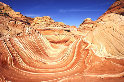 Figure 2.12: The Wave, a series of intersecting U-shaped troughs eroded into Jurassic Navajo Sandstone within the Paria Canyon-Vermilion Cliffs Wilderness, Arizona. The cycling layers in the sandstone represent changes in the direction of prevailing winds as large sand dunes migrated across the desert.