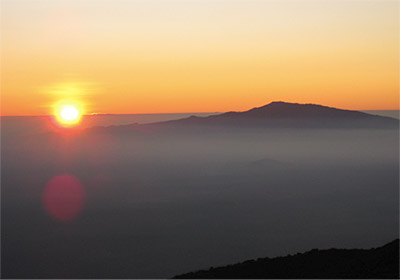 Figure 9.16: Trade wind inversion. The summit of Hualālai, at sunset, rises above the inversion layer while hazy and humid boundary layer air remains below. The Hualālai summit is 2521 meters (8271 feet), and here the inversion is ~1980 meters (~6500 feet).