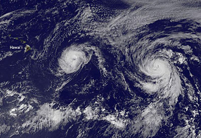 Figure 10.29: NASA MODIS image of hurricanes Iselle (left) and Julio (right) lining up on the Hawaiian Islands, August 6, 2014. Modern hazard forecasting and warning systems reduce the impact on humans.